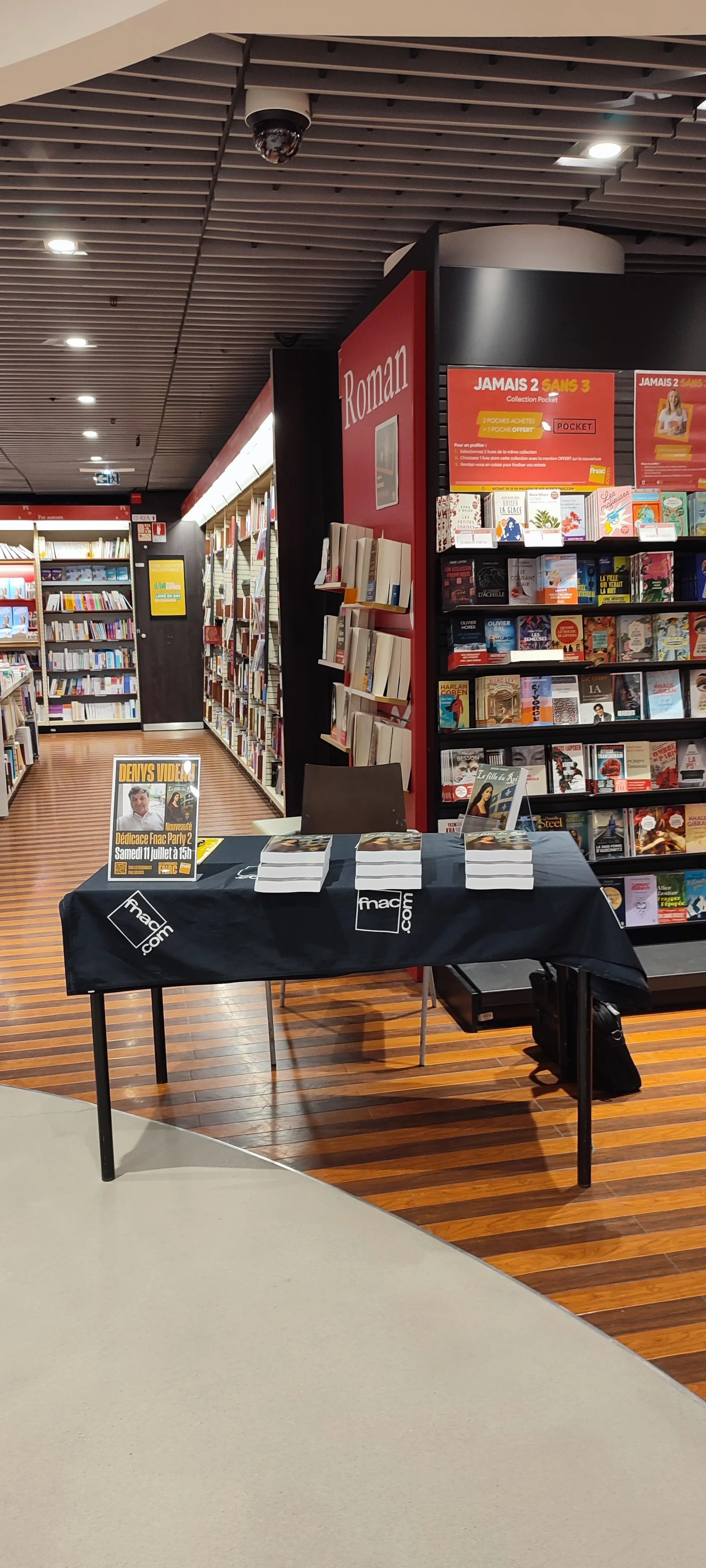 La table de dédicaces nappée aux couleurs de la Fnac, trois piles de La fille du Roi et l’affichette de la séance, devant le rayon Roman
